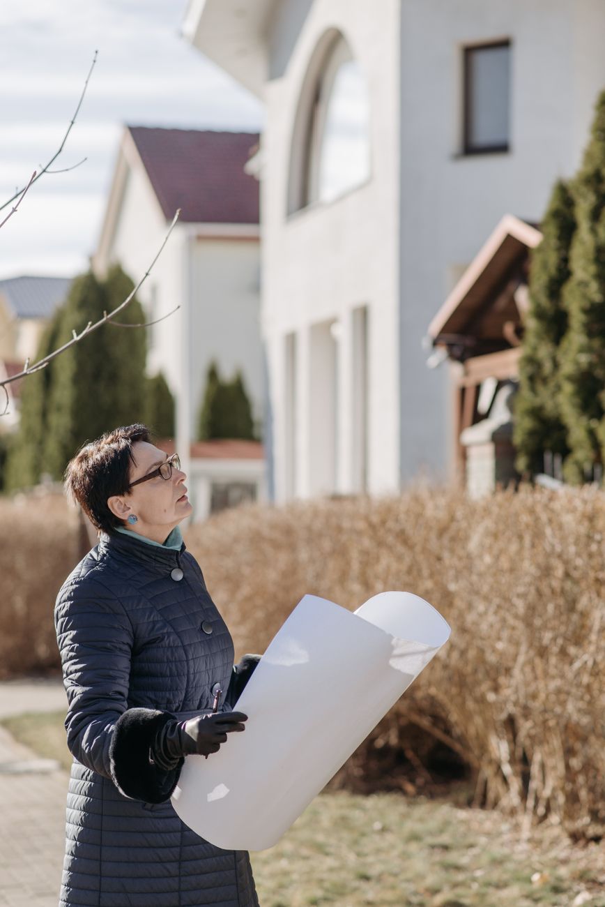 Person holding a plan outside a house